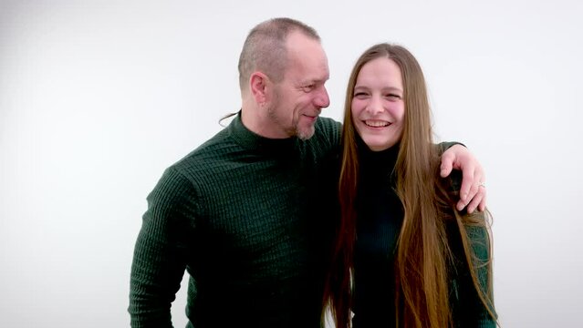 adult man with a beard and mustache laughs hugs a young girl joy happiness fun relationship warm Green clothes on a white background raise a fist up show we are strong we are invincible team sports