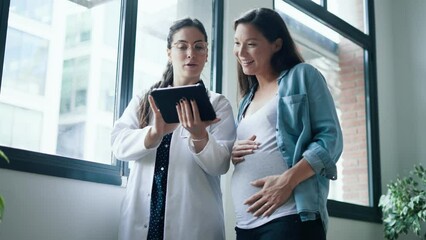Video of female gynecologist doctor showing to pregnant woman ultrasound scan baby with digital tablet in medical consultation.