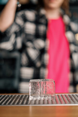 An ice cube stands impressively on the bar The initial stage of cocktail preparation at the bar