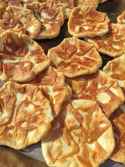 Fried wheat flour pies in a frying pan. Traditional Moldavian and Romanian dish. Balkan cuisine, national pastry. Flat round dough cakes with filling. Fresh treats at the food court. Placinda