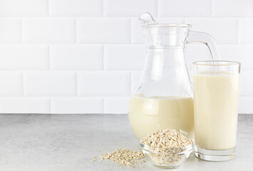 A jug and a glass of oat milk, oatmeal on a white background. Concept of alternative lactose-free...