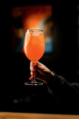 a client of a restaurant bar is holding a delicious Aperol spritz cocktail in his hand close-up