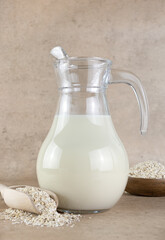 A jug of oat milk, oatmeal on a beige background. Concept of alternative lactose-free dairy products. 