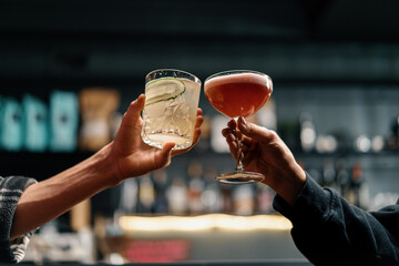 Close up of two people cheering cocktails in a bar or disco club drinks and cocktails concept - obrazy, fototapety, plakaty