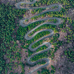 Aerial photography of a winding road in the mountains with serpentines and curves. Photography was shot from a drone at a higher altitude.