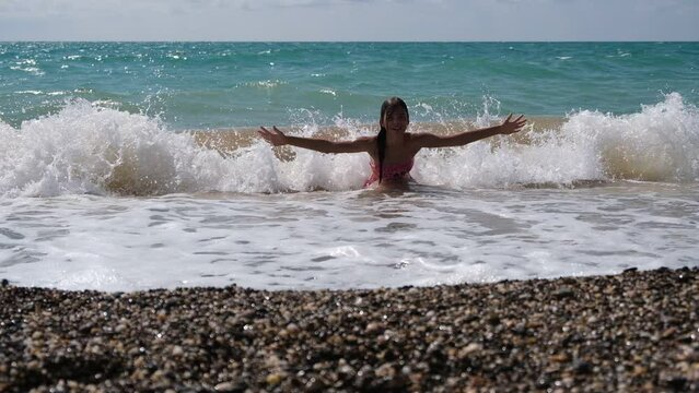 Teenage girl swimming in the sea, having fun, splashing water. A family's Summer Trip. Video 4K.