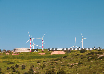 a large field of green grass with wind mills in the background