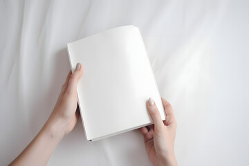 Mains tenant un livre avec une couverture blanche sur un drapé blanc » IA générative - obrazy, fototapety, plakaty