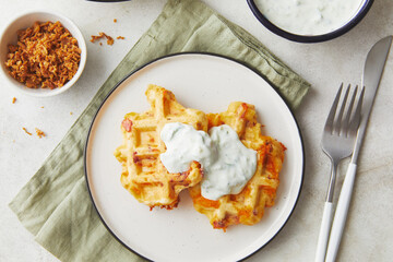 Snack waffles with bacon, cheddar cheese and dried fried onions and tzatziki sauce on light background