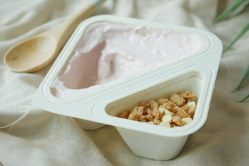fresh yogurt in a plastic container and spoon on table 