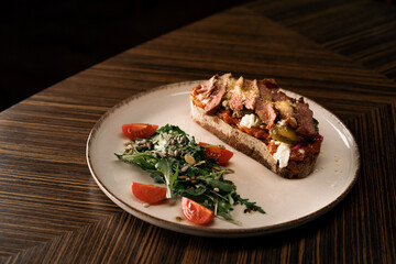 Delicious bruschetta with cheese tomato salad and juicy roast beef in the restaurant Healthy food gastronomy
