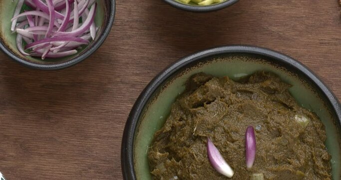 Sarson ka saag traditional Indian dish with corn bread (Makki di roti) with shallots and garlic. Homemade food meal. Table camera slide.