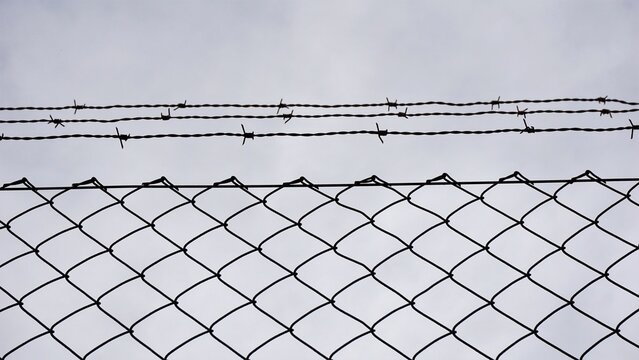 metal grate with barbed wire against sky
