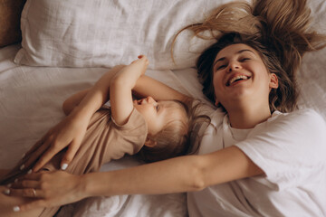 small child plays with mother in bed
