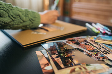 Unrecognizable middle-aged woman writing on a handmade travel kraft paper photo album.