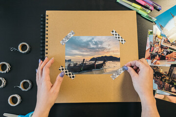 Image seen from above of a middle-aged woman's hands sticking a small piece of washi tape on the...