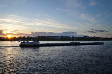 Panorama von D&uuml;sseldorf mit Blick &uuml;ber den Rhein auf ein Frachtschiff im Sonnenuntergang 
