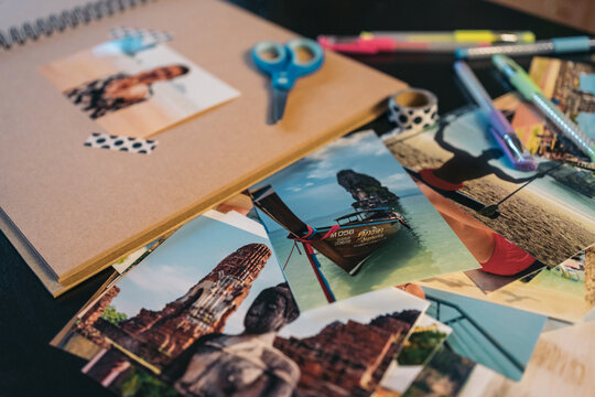 Pile of travel photos next to a brown kraft album ready to be made with washi tape.