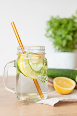 Fototapeta premium Infused water with cucumber, lemon and ginger in glass bottle on wooden table. Diet, detox, healthy eating, weight loss concept
