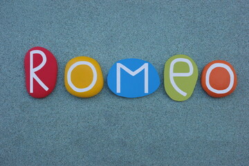 Romeo, masculine given name composed with multi colored stone letters over green sand