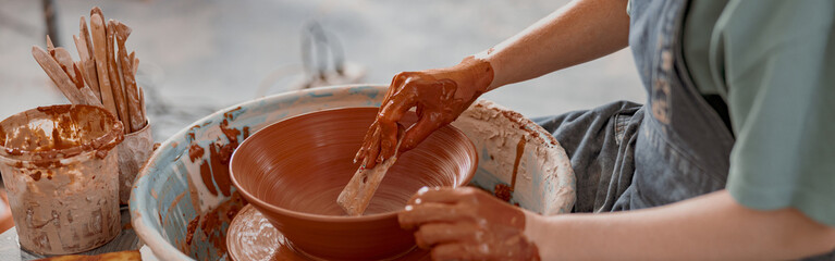 Potter working manually on pottery wheel in workroom