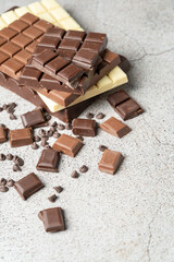 Several chocolate bars one on top of the other of different types, dark, milk and white chocolate on stone top. High quality photo