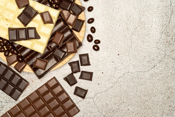 View from above of chocolate bars of different types of chocolate, dark, milk and white on a stone top. High quality photo