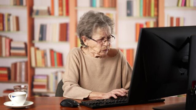 Portrait of angry stressed elderly old woman 80s, using computer gets bad news. Mad female feels frustrated by high bills, bank debt, tax invoice or mistake.