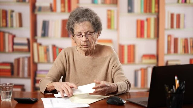 Senior elderly old woman reading paper notice or letter from bank or colleague rejoices with two thumbs up, gets good news receives job offer, concept of success, triumph, winner.