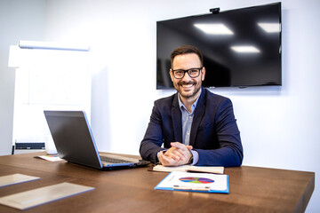 Portrait of smiling businessman sitting in company office.