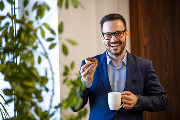 Portrait of businessman having a work break enjoying coffee and donuts. - Powered by Adobe