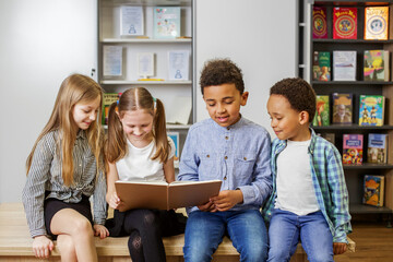 Group happy children reading book in classroom. Back to school. Study and education concept