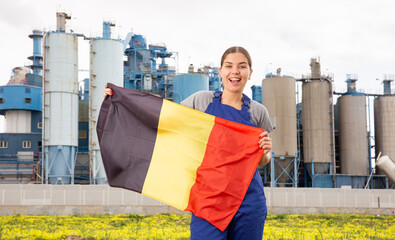 near large industrial enterprise in Belgian outback,jubilant female employee in work overalls...