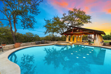 a luxury pool at sunset with a gazebo 