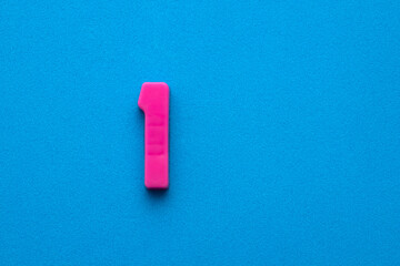 Number one color pink (1) - Plastic digit on blue foamy colored background