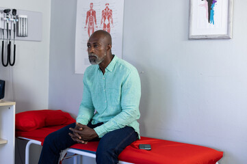 African american male patient sitting on examination couch and waiting at doctor's office