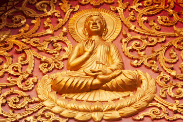 Laos, Luang Prabang. Golden relief carving of Buddha.