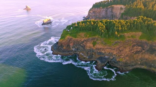 Gorgeous Sunrise Aerial: Cape Meares Lighthouse, Massive Cliffs, Pillar & Pyramid Rocks, Waves Crashing, White Foam, Blue Sky Summer Morning, Oregon Coast