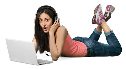 Young woman lying down in front of her laptop with headphones on