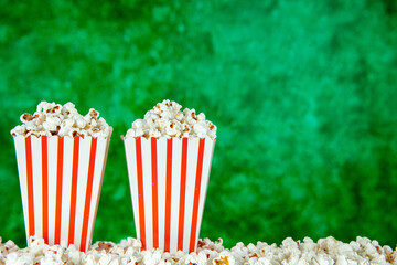 front view fresh popcorn in white and red striped packages on the green background snack cinema...