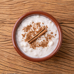Canjica or munguza, typical brazilian white corn sweet cream with cinnamon over wooden table