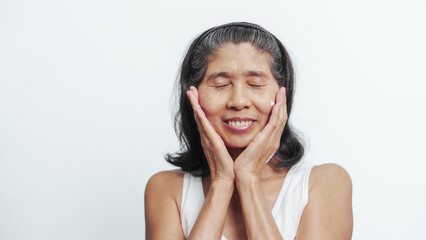 Close up face of female elderly mature older asian chinese housewife applies anti aging facial cream on face, old skincare treatment