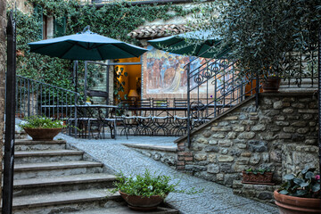 Italy, Umbria, Montone. Small intimate restaurant with outdoor seating and umbrellas.