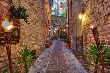 Fototapeta na wymiar Italy, Umbria. Street lined with flower pots in the town of Assisi.