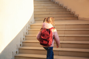 Cute little girl with backpack on stairs outdoors, back view