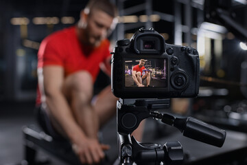 Man recording workout at gym, focus on camera. Online fitness trainer