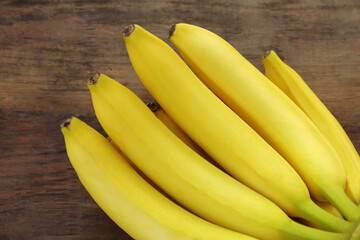 Bunch of ripe yellow bananas on wooden table, closeup