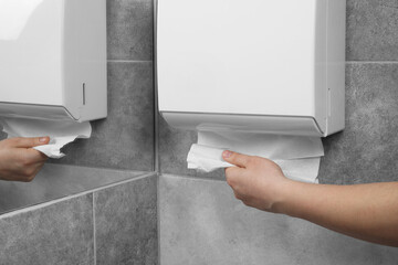 Woman taking new fresh paper towels from dispenser in bathroom, closeup, Space for text