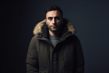 Fototapeta premium Portrait of a handsome young man in a winter jacket on a dark background