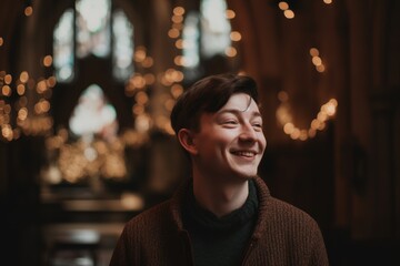 Young man in a brown knitted sweater in a dark Gothic church
